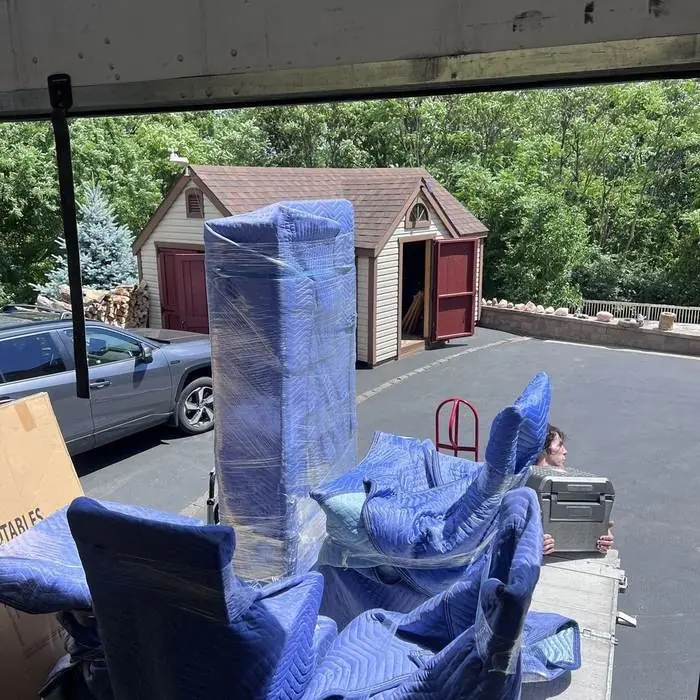 Blanket-wrapped furniture lined up in a driveway before loading
