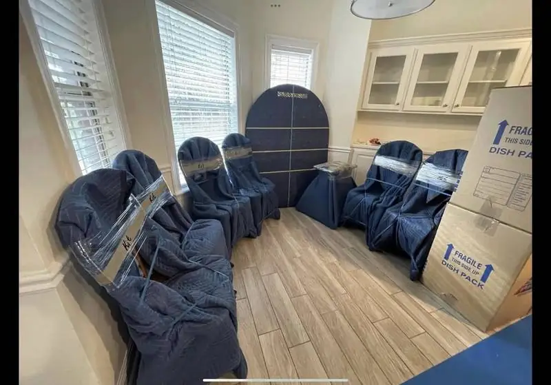 Furniture wrapped in moving blankets in a living room, ready to load